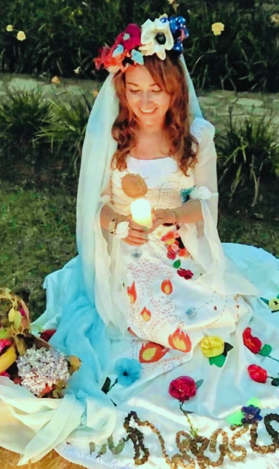 Mujer en ceremonia con corona de flores sosteniendo una vela